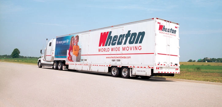 Wheaton World Wide Moving crew with boxes in front of a moving trailer